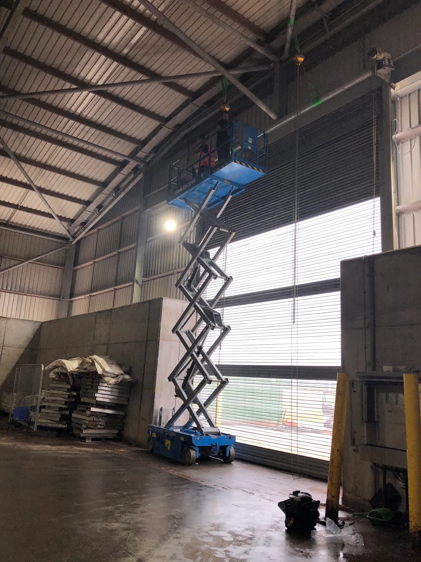 Warehouse roller shutter being installed using a scissor lift